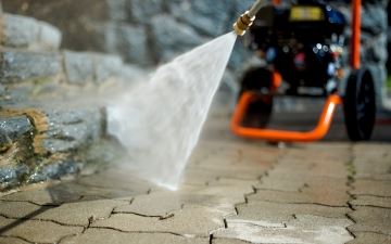A man putting a drainage tube into an outdoor septic tank.
